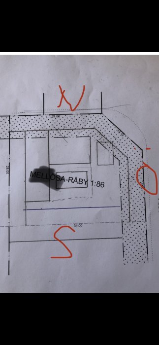 Skiss av en tomtplan med markeringar för tänkt placering av hus och garage i ett L-format arrangemang.