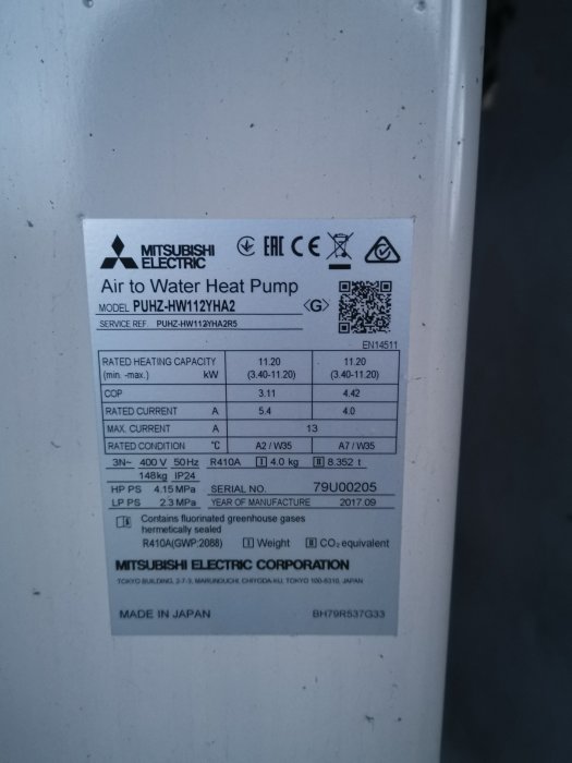 Specifikationsetikett på en Mitsubishi Electric luft-till-vatten-värmepump, modell PUHZ-HW112YHA2, tillverkad i Japan.