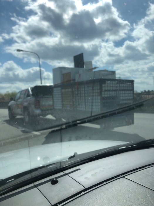 Fordonskombination med lutande släpvagnshjul kör på motorväg, taget genom bilruta.