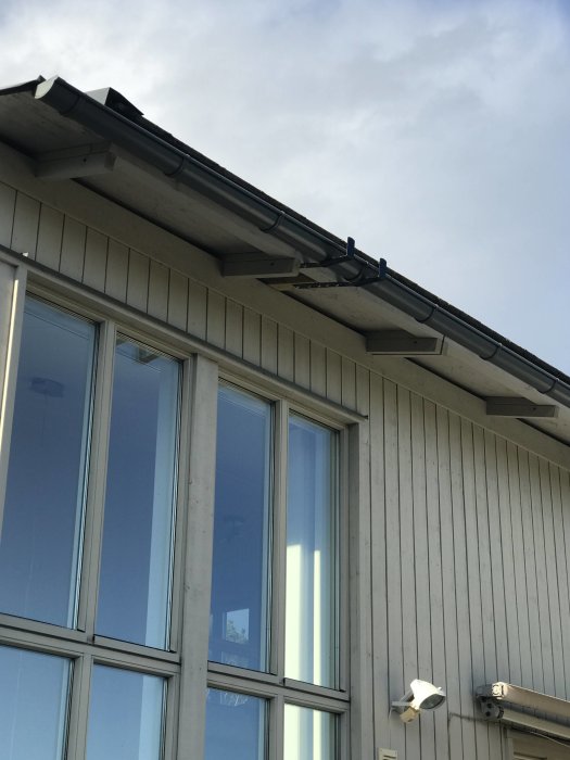 Stegjärn fastsatt på taket av ett hus med säkerhetsutrustning nära hängrännan.