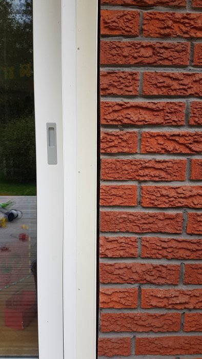 Glapp mellan vit skjutdörr och tegelvägg som visar avståndet där plåt ska ansluta.