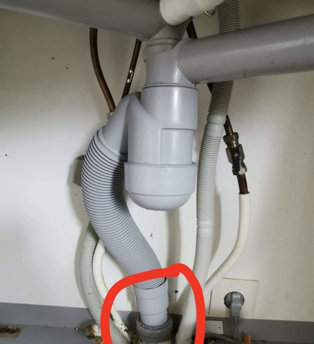 En upplöst bild under diskhon som visar röranslutningar och en slang markerad med röd cirkel där vakuumproblem uppstår.