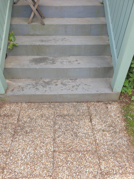 Trappa av betong målad i ljusgrå och blå nyanser med omgivande gröna växter och grusad gångväg.