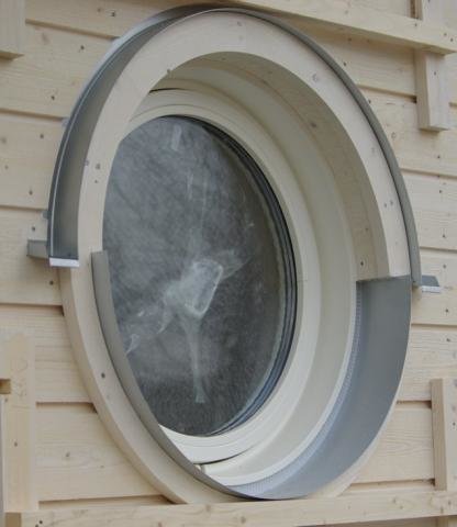 Runt fönsterbleck och överbleck monterat på ett runt fönster på trävägg.