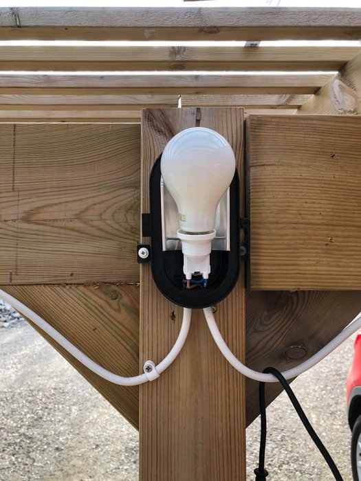 LED-lampa för stor för befintlig armatur monterad på trävägg av en carport.