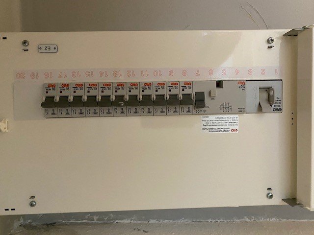 Elcentral med öppen dörr som visar säkringar och etiketter för olika kretsar.