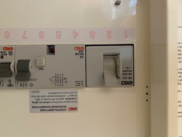 Elcentral med öppen dörr och synliga säkringar samt installationsanvisningar.