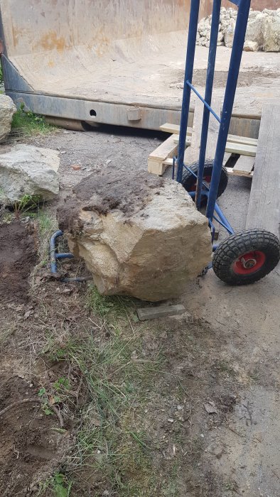 Blå stenbärare med stora hjul tar sig an en tung sten på ett bygge.
