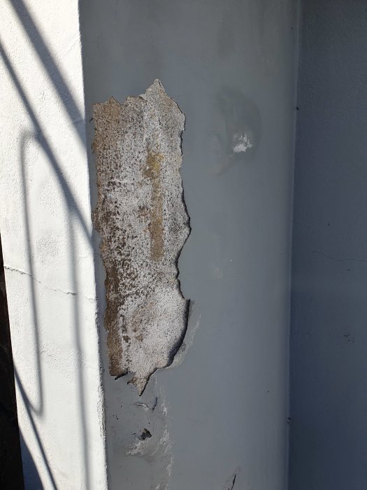 Avflagande färg och bubblor på en yttervägg orsakade av fukt.
