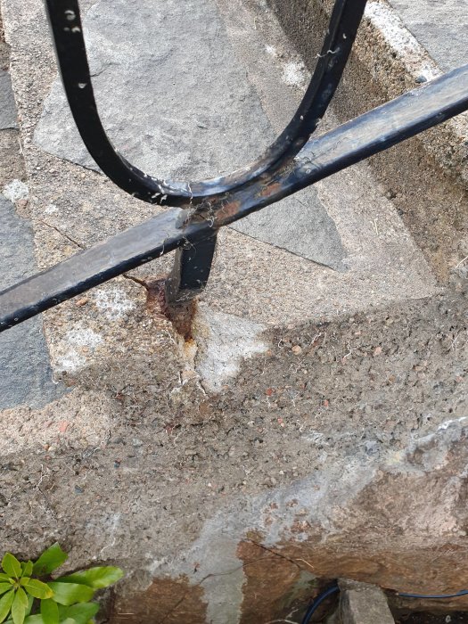 Spricka i betongtrappa vid svetsning av metallräcke, behöver repareras.