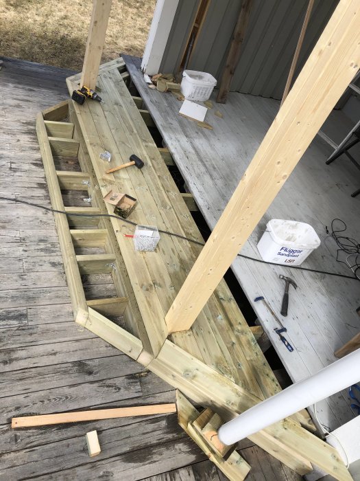 Byggplats med trästomme och verktyg på ett trädäck, förberedelse för installation av bärlina.