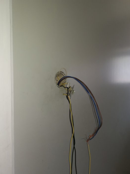 Elektriska kablar och ledningar som hänger lös från ett vägguttag under installation eller reparation.