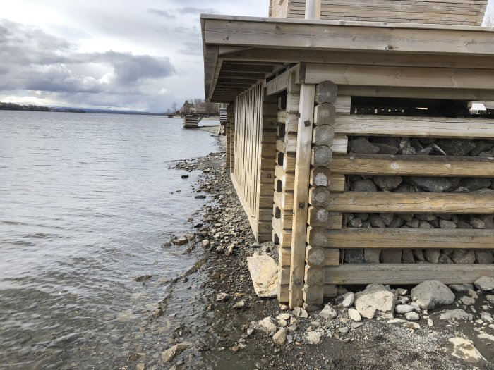 Stenfyllning under träbrygga vid sjö för att underlätta underhåll på våren.
