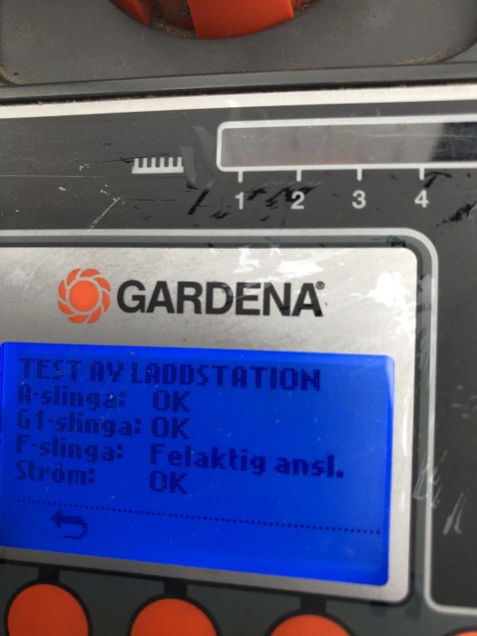 Närbild av en Gardena robotgräsklippares display som visar testresultat med "Felaktig ansl." för F-slinga.