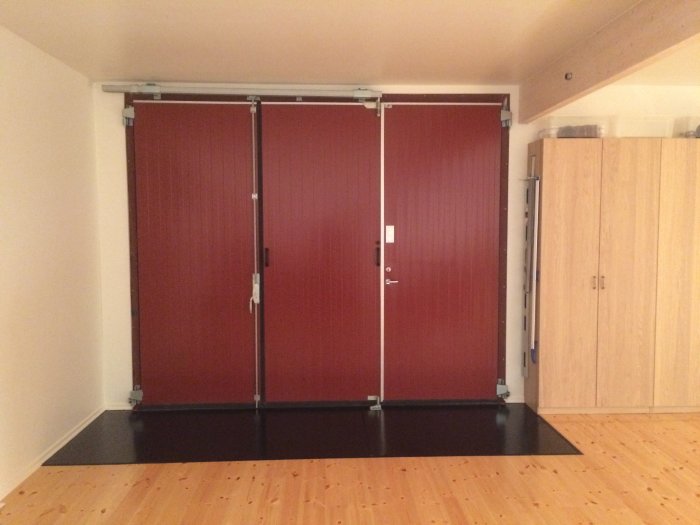 Nylagt och lackat flytande furugolv i en verkstad med röd dubbeldörr och träskåp.