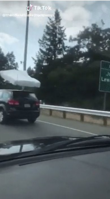 En stor rund föremål surrad ovanpå en körande SUV på en väg.