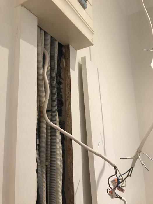 Exposed electrical wires and conduit next to a dismantled closet area with an electrical cabinet.