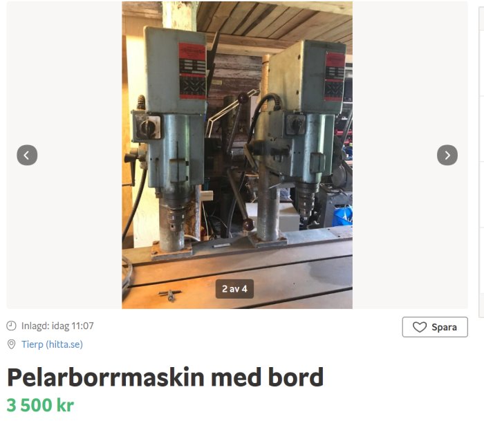 Två gröna pelarborrmaskiner monterade på ett gemensamt träbord i ett verkstadsutrymme.