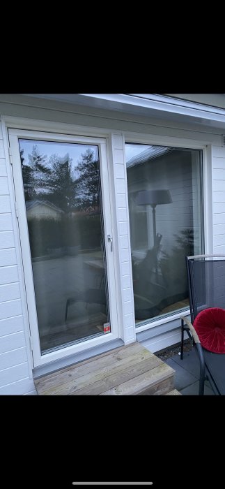 Bild av ett fönster på en husvägg med vit liggande panel utan fönsterbleck och synliga salningar.
