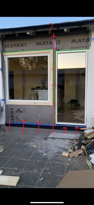 Husfasad med ett pågående isoleringsarbete runt fönster, med röda pilar som indikerar luftflöde.
