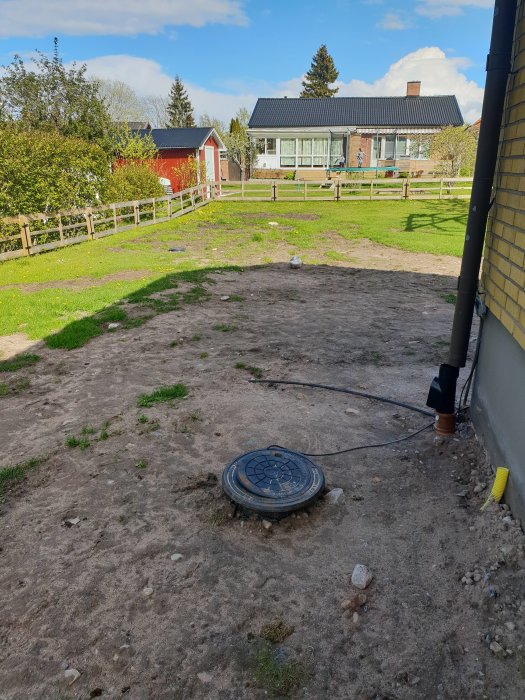 En stenkista med öppet lock i en trädgård nära ett hus, med stuprör som leder vatten till den.