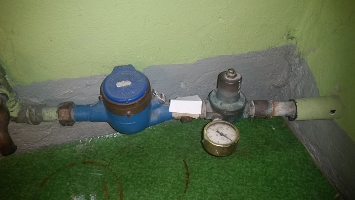 Vattenmätare och tryckregulator med manometer i ett vattenledningssystem.