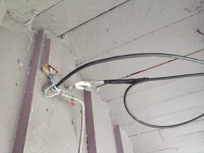 Ledningar med osäkert syfte fästa vid en husvägg, eventuellt telefon- eller elledning.