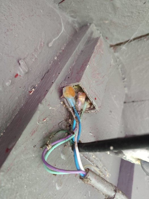 Ledningsfäste på husvägg med flera slingrande kablar, varav några är anslutna med skarvklämmor.