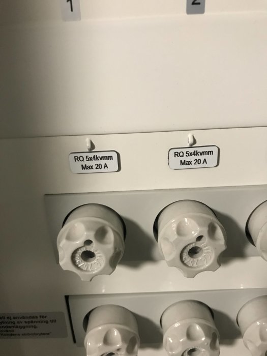 Elskåp med säkringshuvuden och etiketter som visar "RQ 5x4kvmm Max 20 A".