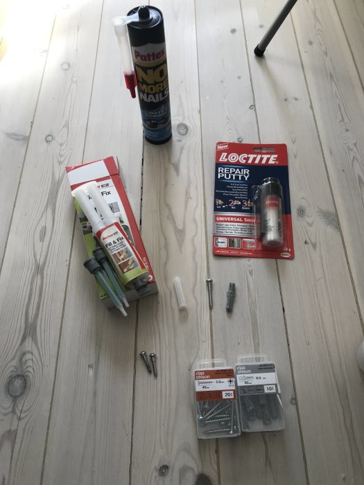 Ett urval av byggmaterial på trägolv inklusive Loctite Repair Putty, Fischer Fix & Fill, Pattex No More Nails, skruvar och väggpluggar.