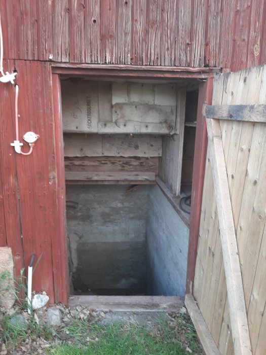 Trappa som leder ner till en källare med delvis rivet tak och rödfärgad vägg.