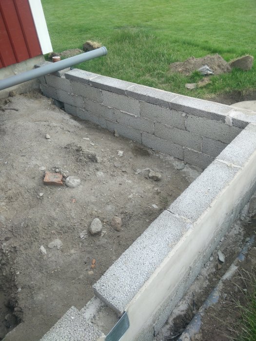 Grund till byggnad under konstruktion med betongblock och grus.