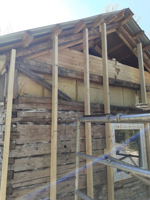 Fasadrenovering på ett torp med reglar för isolering och befintlig vägg med lösull synlig.