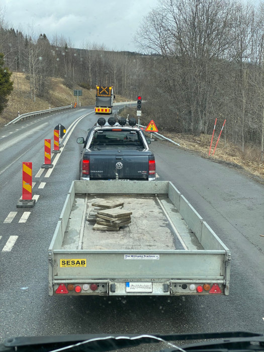 Släpvagn med dålig lastsäkring, få lösa plankor på flaket utan säkring, vid vägarbetsområde.