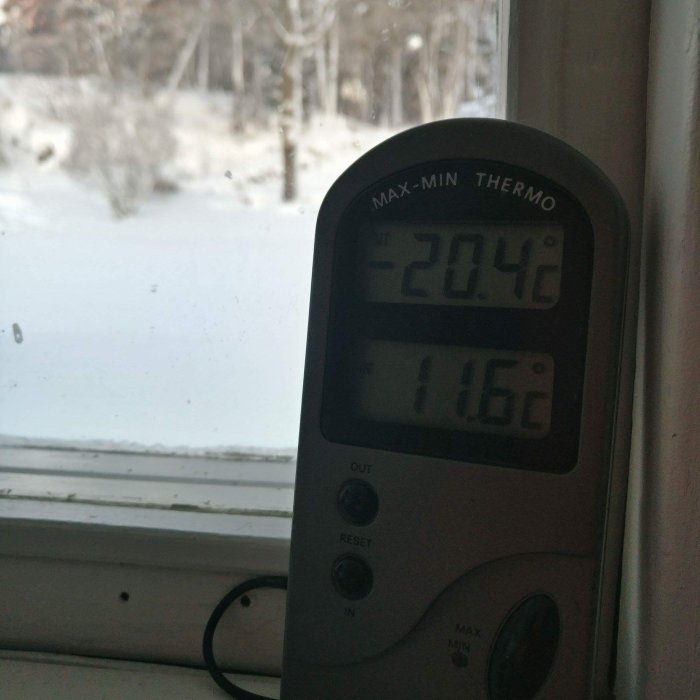 Termometer visar -20,4°C utomhus och 11,6°C inne, med snöig utsikt genom fönstret.