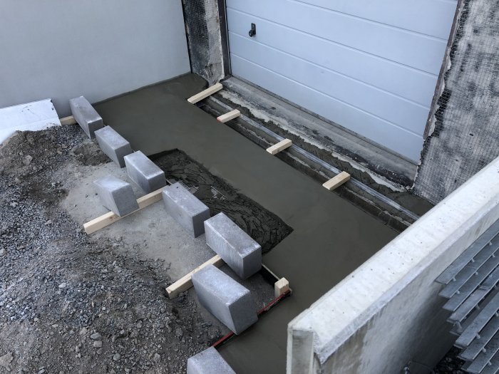 Nyutgjuten finbetong för garageinfart med armeringsnät och betongblock som fixerar ramen.