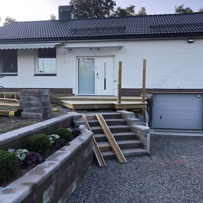Byggprocess av frukostaltan med unika vinklar, stensteg, skrapgaller och träråmaterial framför hus.