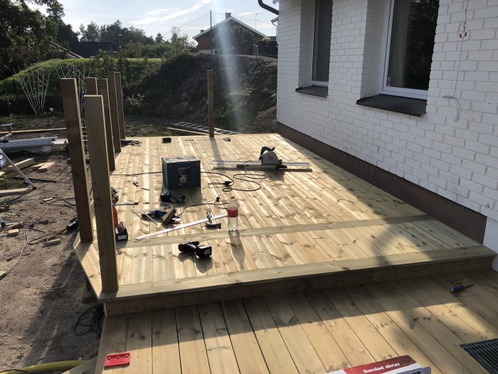 Nästan färdiglagd trätrall med verktyg och byggmaterial runtomkring nära husvägg.