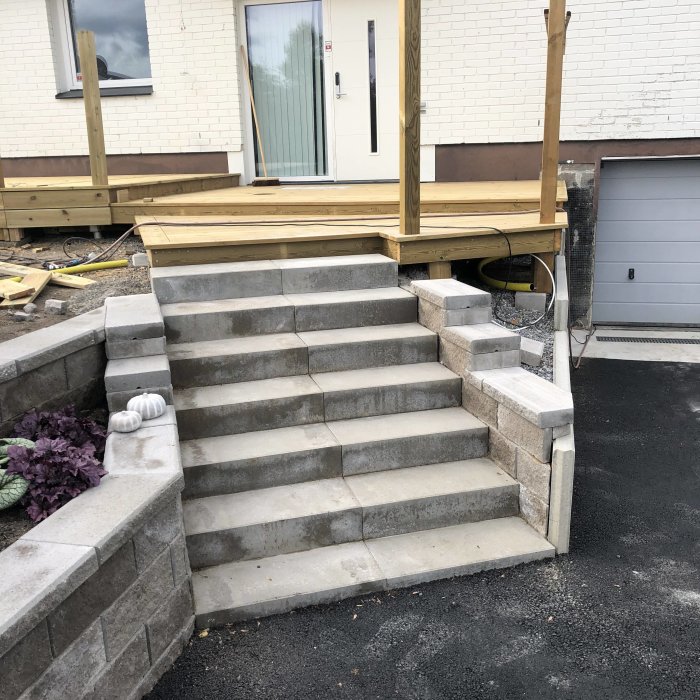 Nybyggda stentrappor framför en terrass under konstruktion med synlig belysningsinstallation.