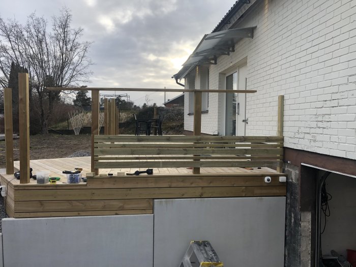 Nybyggt trätrall med säkerhetsräcke vid en vit tegelvilla för att förhindra att ett barn faller.