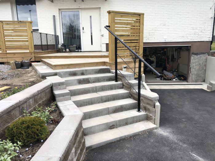 Nyinstallerade betongtrappsteg vid gräsmatta med anpassat svart räcke.