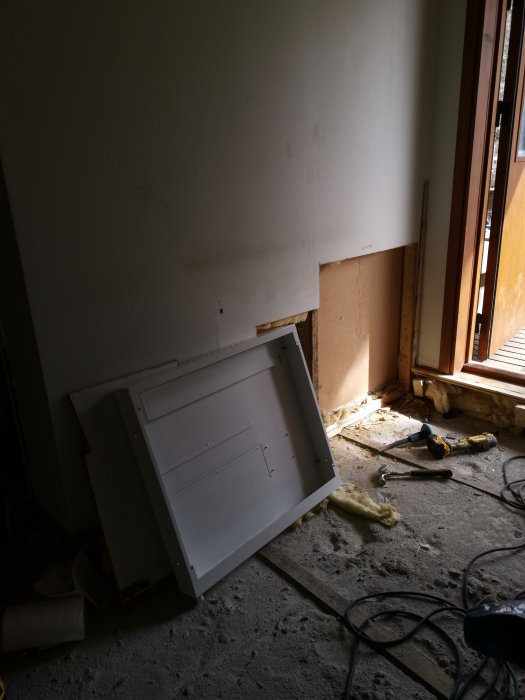 Ett LK schuntskåp ligger på ett betonggolv vid en halvfärdig vägg med verktyg omkring.