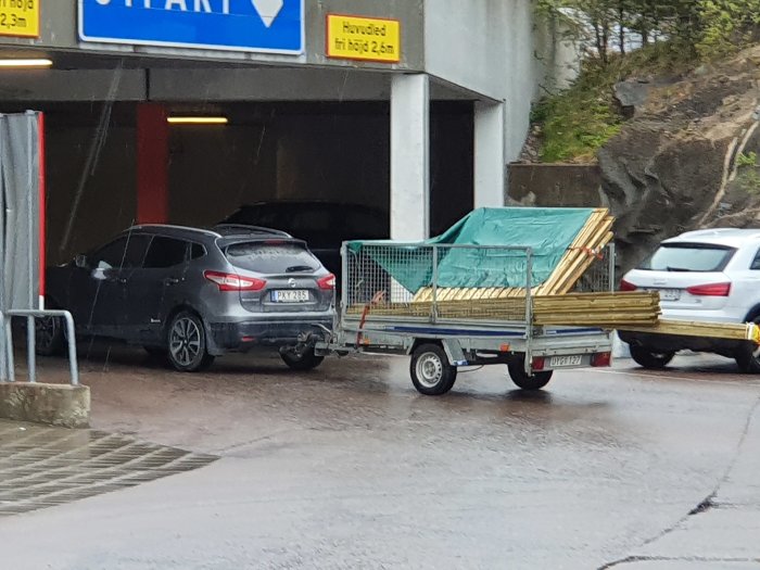 Släpvagn lastad med träplank parkerad utanför en byggmarknad i Arninge.