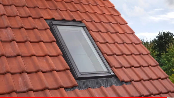 Takfönster Velux Solo 2 installerat i ett rött tegelpanntak, intäckt runt kanterna.