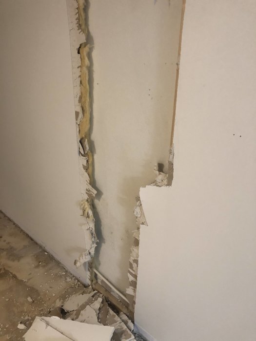 Skadad vägg i källare där isolering och träreglar mot en blöt yttervägg syns efter rivning.
