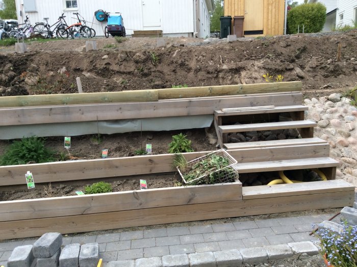 Trädgårdsprojekt med ett staket på en sluttning och träblomlådor för plantering längs backen.