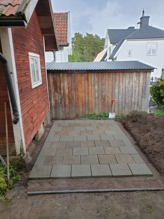 Nyomlagd stenplattsgång med mix av gamla och nya stenar mellan två byggnader.