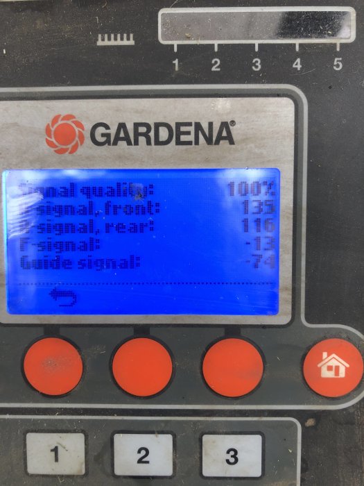 Närbild av en Gardena laddningsstation display som visar signalvärden; använd och sliten med fysiska knappar under skärmen.