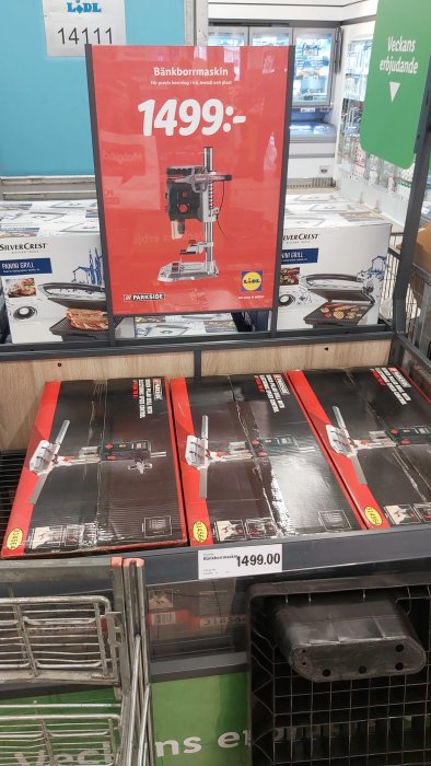 Bänkborrmaskiner i förpackning i butik med skylt som visar pris 1499 SEK.