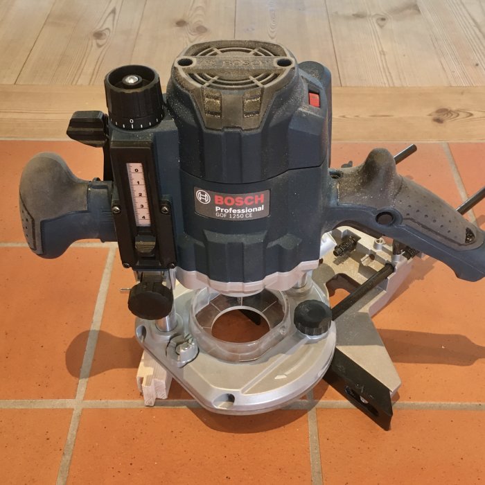 Bosch Professional GOF 1250 CE handöverfräs på ett kakelgolv.